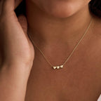 Gold necklace with heart pendants worn by a person