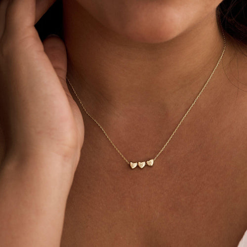 Gold necklace with heart pendants worn by a person