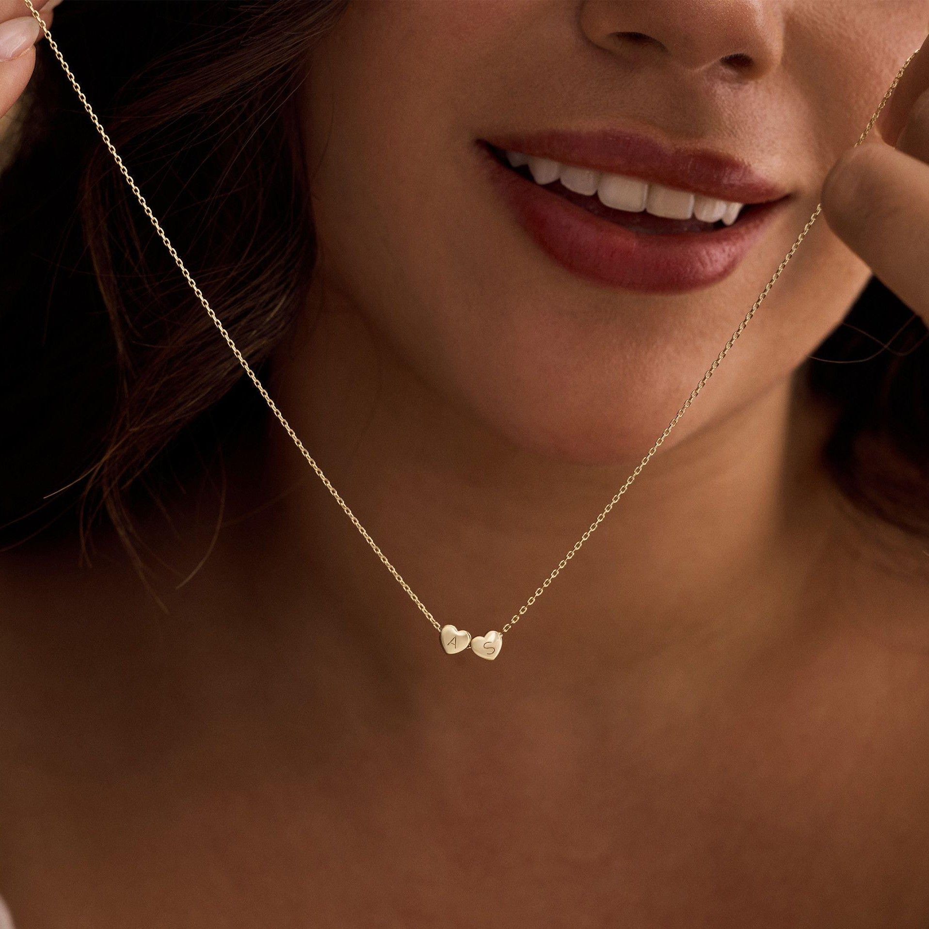 Close-up of a woman wearing a gold necklace with heart pendants.